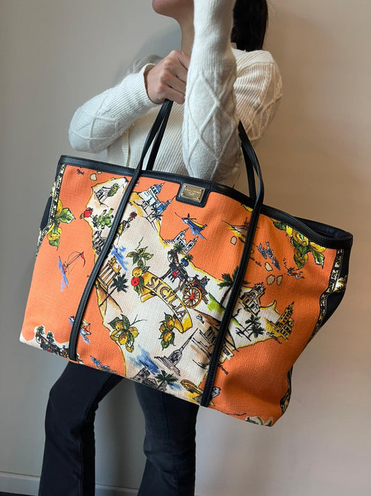 indossata Borsa Dolce & Gabbana in tessuto arancione con iconica grafica ispirata alla Sicilia, finiture in pelle nere e parti metalliche dorate; munita di doppi manici e una pochette estraibile. Completa di dustbag, originale, di lusso, ottime condizioni.