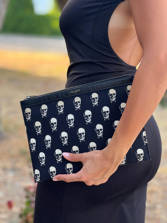 Pochette Saint Laurent in tessuto nero con stampa teschi su tutta la superficie, rifinita con parti metalliche argentate, indossata