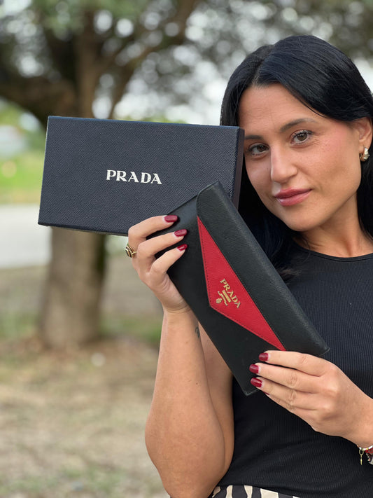 indossata Portafoglio Prada in pelle saffiano nera e rossa con parti metalliche dorate; munito di un portamonete estraibile. Completo di scatola logata e card d'autenticità.