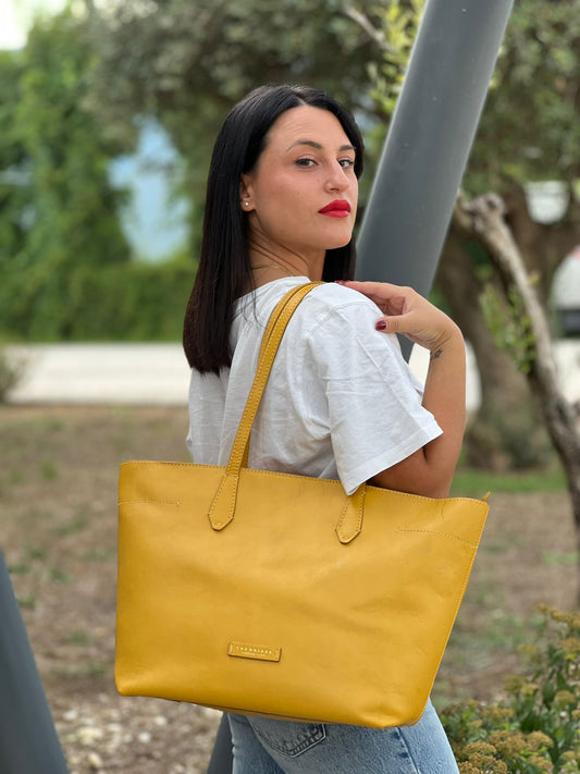 indossata Borsa The Bridge in pelle gialla con parti metalliche dorate; munita di doppi manici, da indossare a spalla