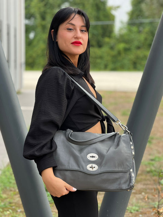 Ragazza che indossa Borsa Zanellato in pelle martellata grigia con parti metalliche argentate. Munita di un mono manico e una tracolla regolabile, e amovibile.