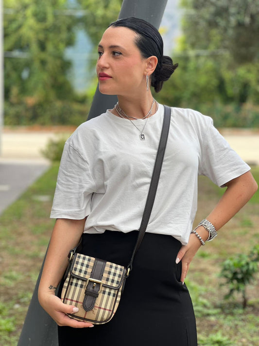 Ragazza chi indossa Tracolla Burberry in canvas beige trama tartan con stampa house check e finiture color marrone testa di moro e parti metalliche dorate.