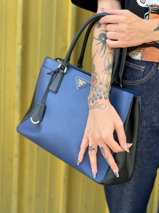 indossata interno Borsa Prada in pelle saffiano blu e nera con parti metalliche dorate; munita di doppi manici stondati e impreziosita da un portachiavi. Completa di dustbag, di lusso, originale, ottime condizoni, usata.
