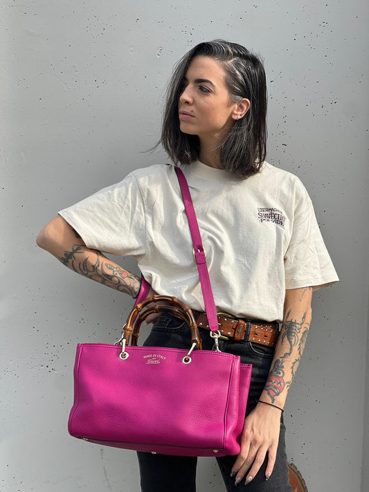 indossata Borsa Gucci in pelle martellata fucsia con parti metalliche dorate; munita di doppi manici in bamboo e una tracolla amovibile e regolabile, di lusso, ottime condizioni, usata.