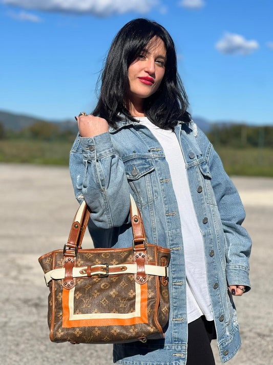 Ragazza chi indossa Borsa Louis Vuitton Tisse Rayures in tela monogram arricchita da finiture in pelle color cognac e crema con dettagli metalliche dorate; munita di due manici in pelle. Completa di scatola e dustbag. Originale, usata, di lusso, in ottime condizioni