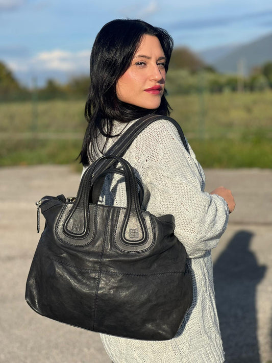 Ragazza che indossa Borsa Givenchy Nightingale in pelle blu notte e parti metalliche dorate. Munita di doppi manici e tracolla una amovibile arricchita da una cerniera decorativa. Indossabile a mano o a tracolla. Originale, usata, di lusso, in ottime condizioni