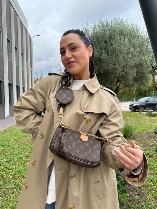 Ragazza che indossa l'Iconica Multi Pochette Accessoires Louis Vuitton in canvas marrone monogram con dettagli in vacchetta naturale, manico in catena dorata e tracolla in tessuto Jacquard verde kaki. Dotata del classico mini portamonete rotondo, rimovibile. Completa di scatola. Originale, usata, di lusso, in ottime condizioni