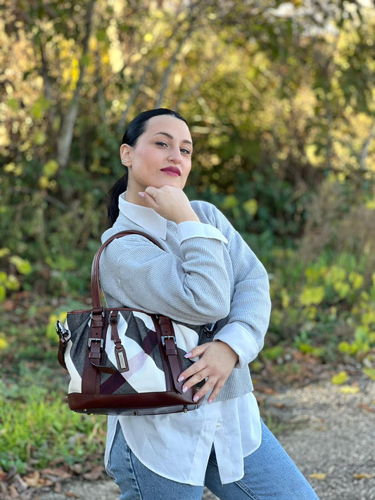 Ragazza che indossa una Borsa Tote Burberry in tessuto bianco trama tartan nera e rossa, finiture in pelle marrone e parti metalliche effetto renio, munita di doppie manici e una tracolla regolabile, amovibile con spallaccio. Indossabile a spalla. Originale, usata, di lusso, in ottime condizioni.