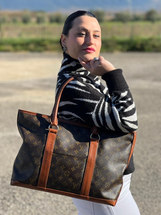 Ragazza che indossa Sac Weekend Louis Vuitton in canvas marrone monogram con doppi manici stondati e parti metalliche dorate. Indossabile a mano. Originale, usata, di lusso, in ottime condizioni.