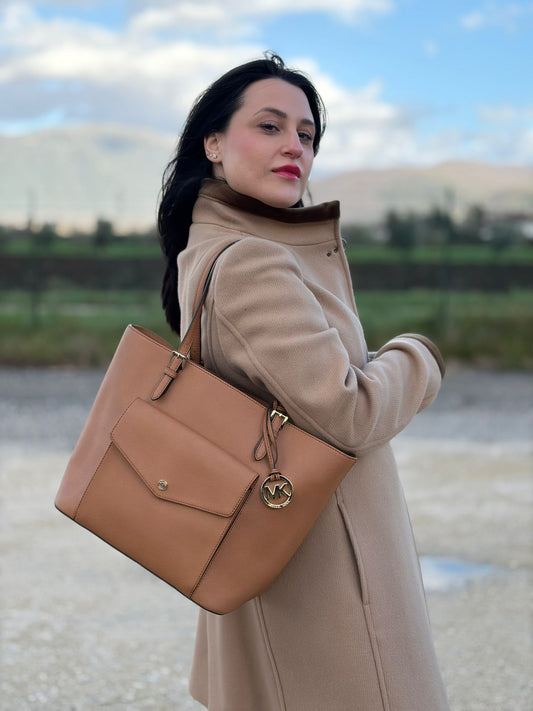Ragazza che indossa una Borsa Michael Kors in pelle saffiano color cammello con parti metalliche dorate; munita di doppi manici. Indossabile a spalla. Origianle, usata, di lusso, in ottime condizioni