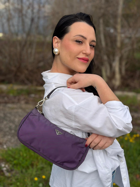 Ragazza che indossa una borsa Prada in nylon viola, indossabile a spalla, usata, originale, second hand, in ottime condizioni.