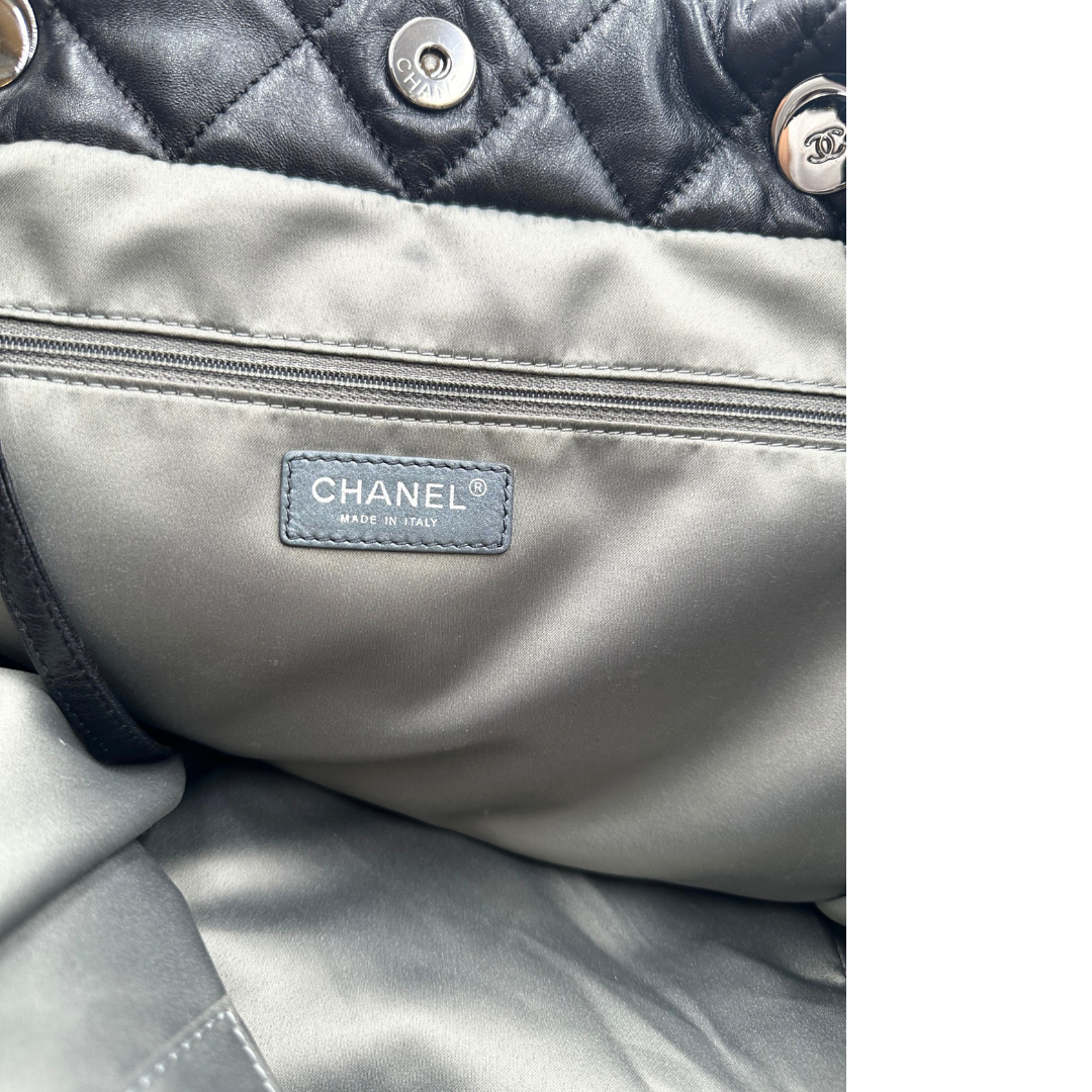 Interno di una borsa tote Chanel Week End On Mars in pelle matelassé nera, con pochette interna e rifinita con parti metalliche argentate.