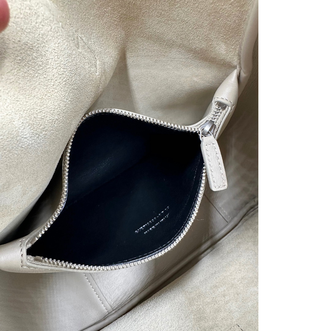 Tasca interna della Borsa Saint Laurent LE 5 À 7 Piccola in pelle martellata beige dotata di manico regolabile con fibbia e rifinita con parti metalliche argentate e iconico logo Cassandre sulla chiusura. Completa di corredo. Originale, usato, in condizioni eccellenti.