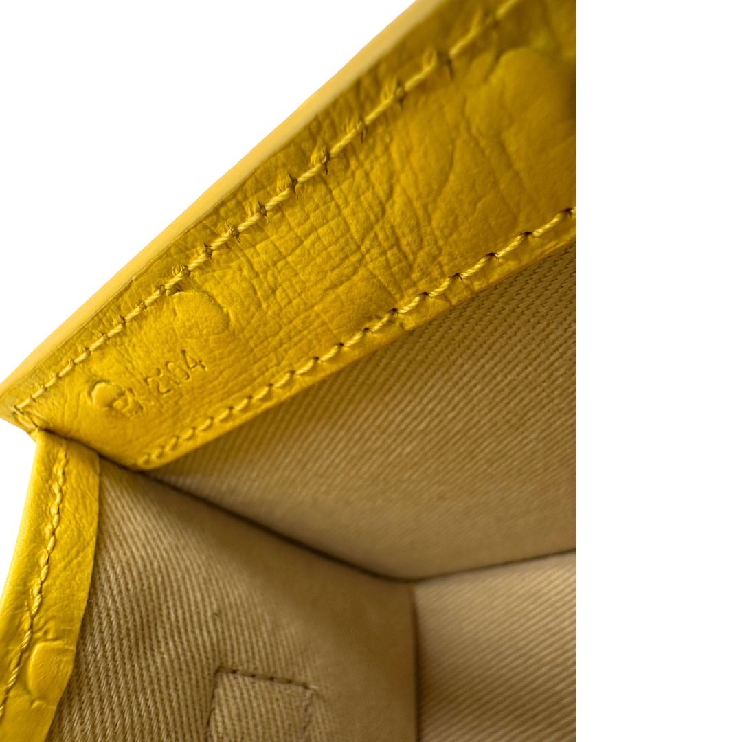 Borsa Jacquemus in pelle gialla goffrata effetto struzzo, con parti metalliche argentate munita di un manico singolo e una tracolla regolabile e amovibile.