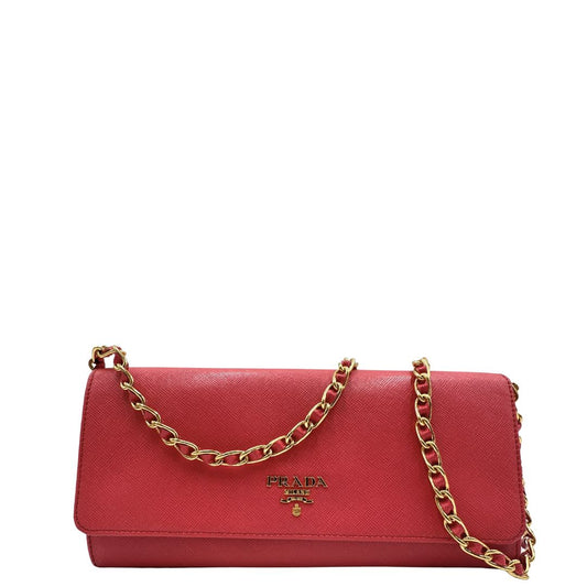 Wallet On Chain Prada in pelle Saffiano rosa fragola con parti metalliche dorate. Munito di una tracolla amovibile in catena e pelle intrecciata. Completo di scatola. Originale, usato, in condizioni ottime.