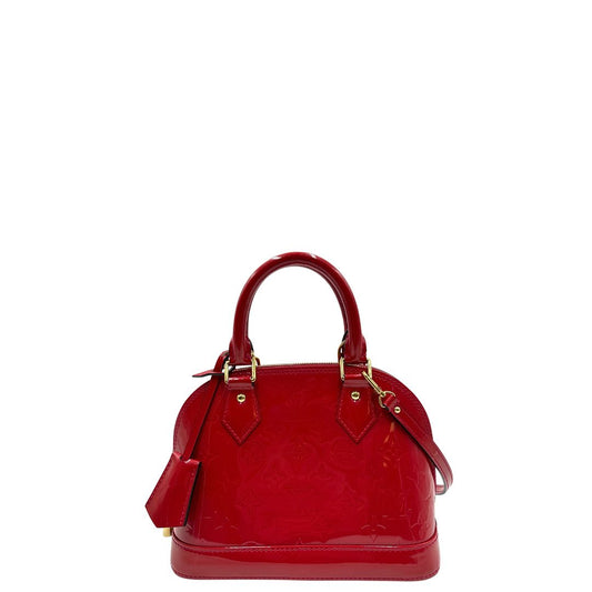 front Borsa Louis Vuitton Alma BB in pelle vernis rossa con trama monogram empreinte e parti metalliche dorate. Munita di doppi manici stondati e tracolla amovibile, dotata di clochette porta chiavi. Completa di scatola, lucchetto e chiavi, di lusso, originale, ottime condizioni.
