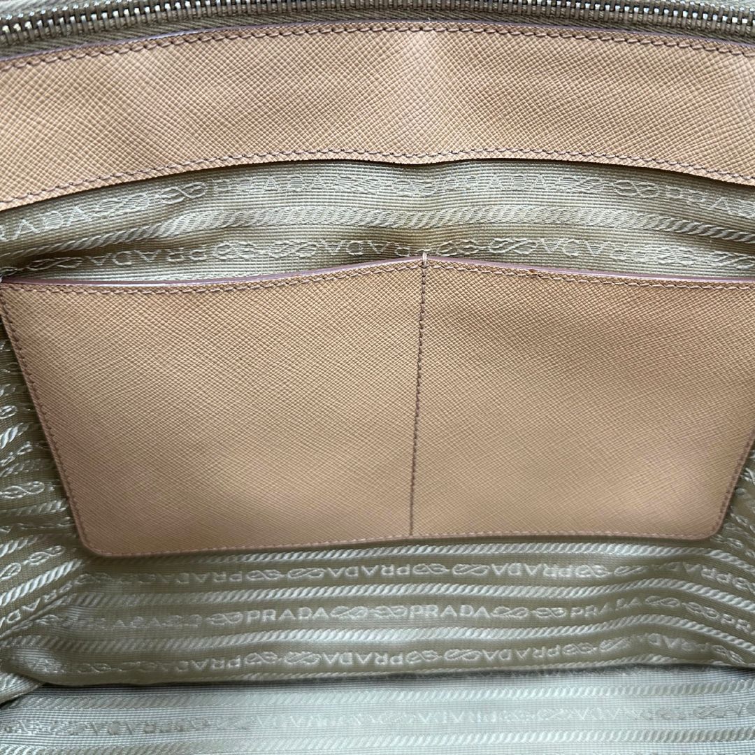 interno Borsa Prada in pelle saffiano color nocciola con parti metalliche dorate; munita di doppi manici stondati e impreziosita da una clochette portachiavi. Completa di dustbag, di lusso, originale, buone condizioni.