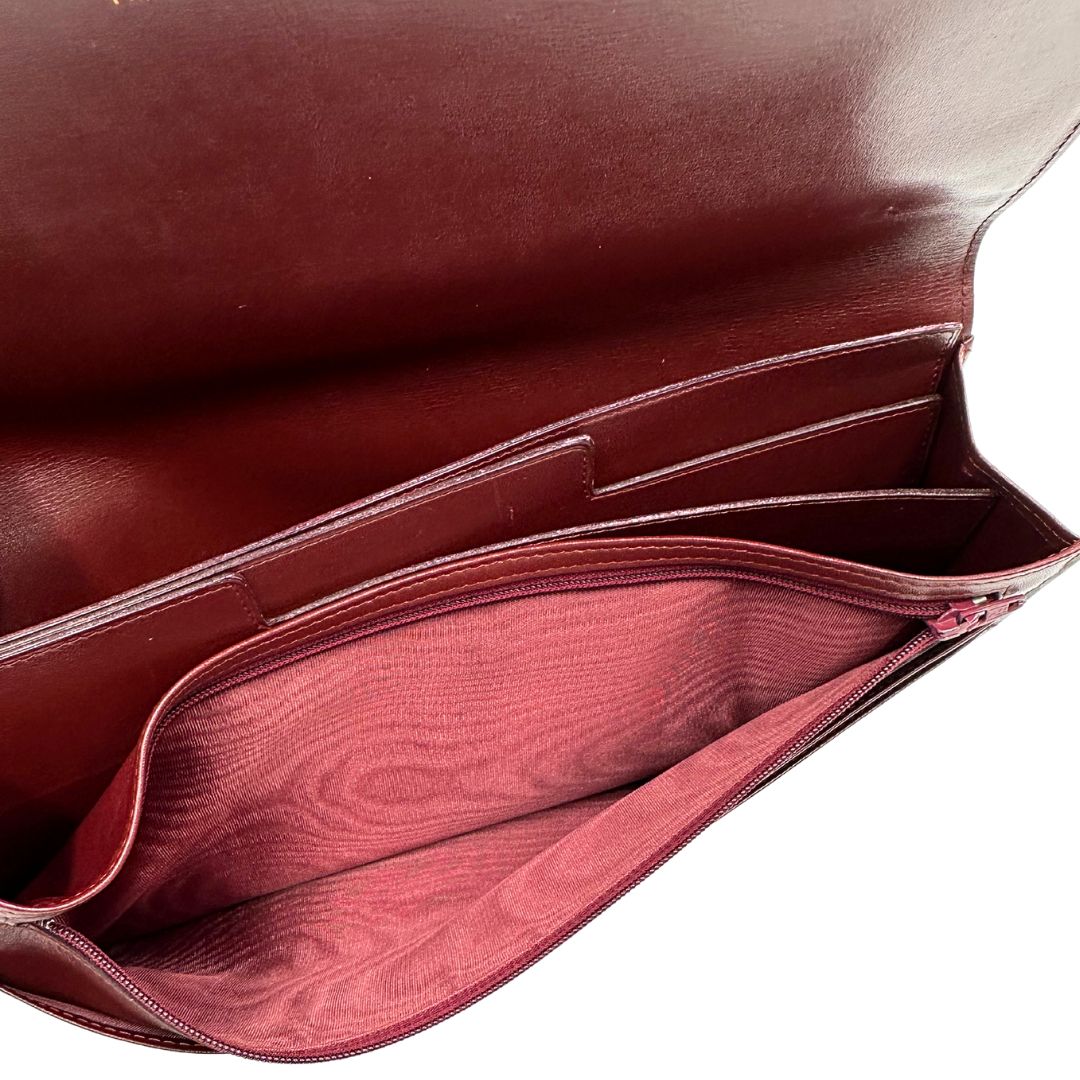 interni Clutch Les Must de Cartier in pelle bordeaux con parti metalliche dorate. Munito di scatola, di lusso, originale.