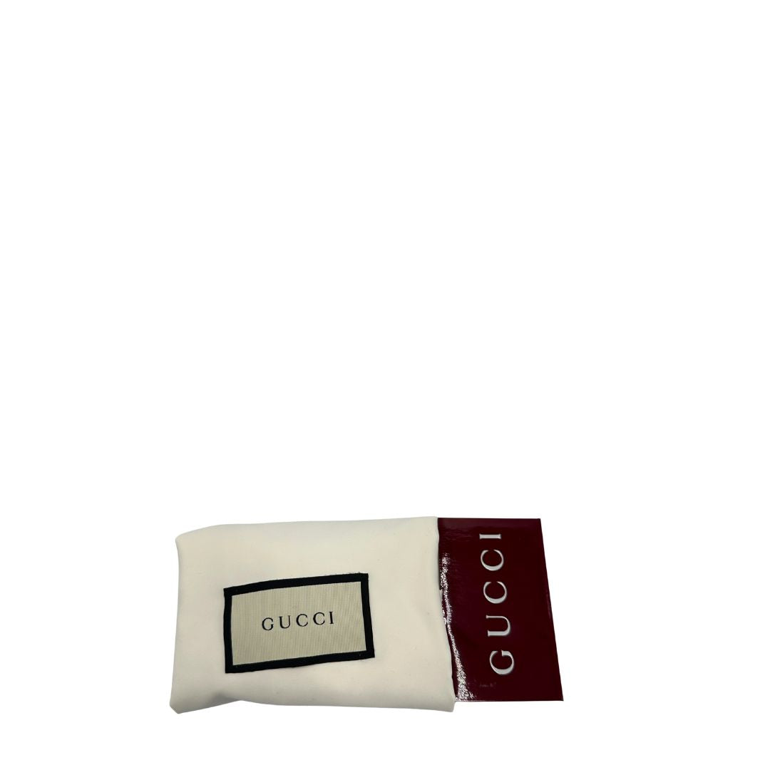 Dustbag di uno zaino Gucci in canvas beige GG con finiture in pelle marroni e parti metalliche dorate. Iconica striscia Web in verde/rosso sulla patta, impreziosita da un manico in catena amovibile e cinghie in pelle regolabili.