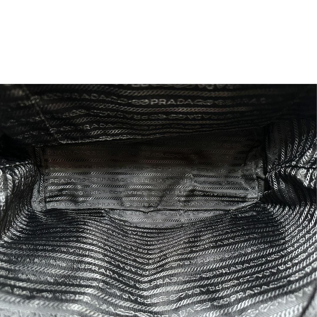 Interno di un Zaino Prada in tessuto nylon nero e finiture in pelle saffiano tono su tono. Parti metalliche argentate; munito di doppie bretelle in tessuto regolabili. Completo di corredo e card d'autenticità. Originale, usato, di lusso, in condizioni eccellenti.