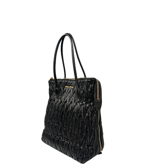 Lato sinistro di una Borsa Miu Miu realizzata in pelle goffrata nera con parti metalliche dorate; munita di due manici stondati, indossabile a spalla. Originale,, usata, di lusso, in ottime condizioni.