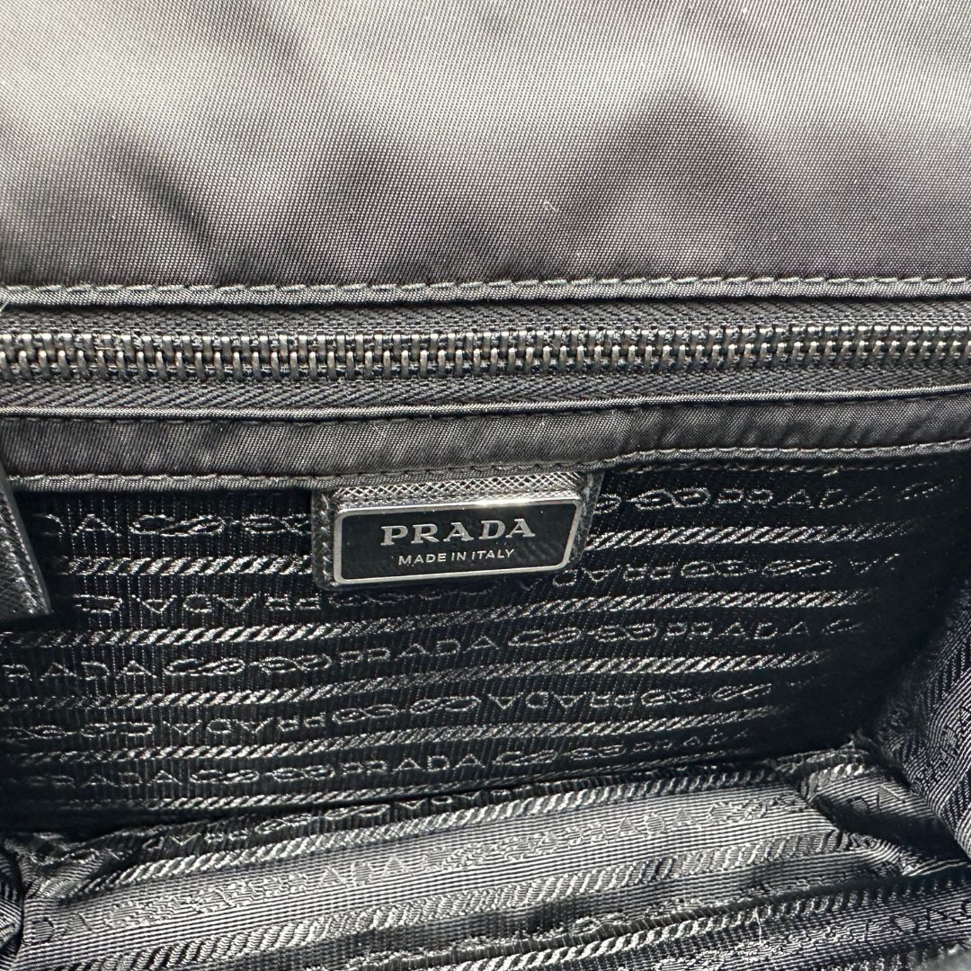 interni Borsa Prada in nylon nero con finiture in pelle saffiano tono su tono e parti metalliche argentate; munita di una tracolla regolabile in tessuto e un pouch rimovibile. Completa di scatola, di lusso, originale, eccellenti condizioni.