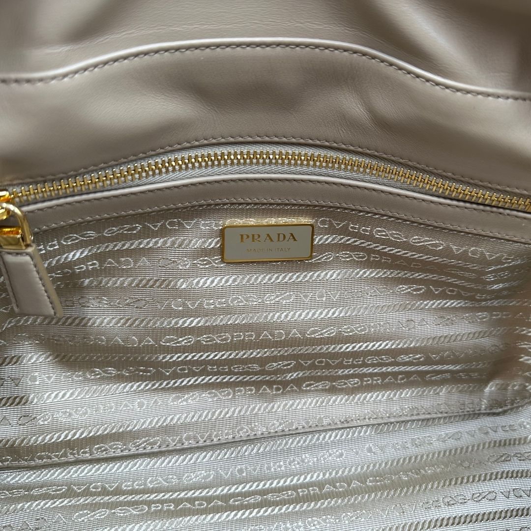 interno della Borsa Prada in nylon beige con finiture in pelle tono su tono e parti metalliche dorate; munita di doppi manici sottili e stondati, indossabile a spalla. Completa di chiavi, lucchetto, cartellini e dustbag, di lusso, originale, ottime condizioni.