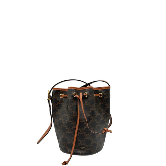 Front di un Secchiello Celine in canvas monogrammato Triomphe con finiture in pelle cognac, presenta chiusura con coulisse e dettagli metallici dorati. Indossabile a tracolla. Originale, usato, di lusso, in condizioni eccellenti.