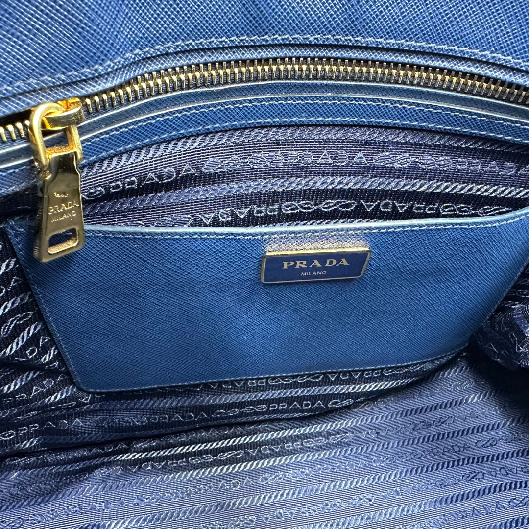 interno Borsa Prada in pelle saffiano blu con parti metalliche dorate; munita di doppi manici stondati, una tracolla amovibile e regolabile e impreziosita da un portachiavi, usata, originale, ottime condizioni.