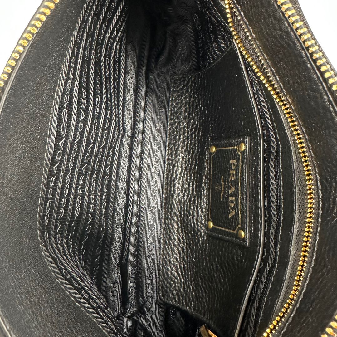 interno Borsa Prada in pelle martellata nera con parti metalliche dorate; munita di una tracolla amovibile e regolabile, da portare a mano, a spalla o a tracolla. Completa di dustbag, di lusso, originale, eccellenti condizioni, usata.