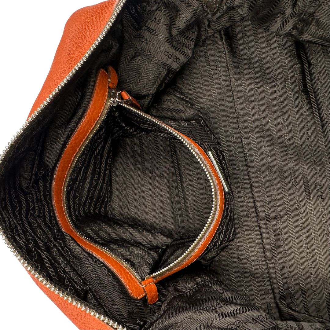 interno Borsa Prada in pelle martellata color cognac con parti metalliche argentate; munita di doppi manici, indossabile a spalla. Completa di lucchetto e chiavi, di lusso, originale, ottime condizioni, usata.