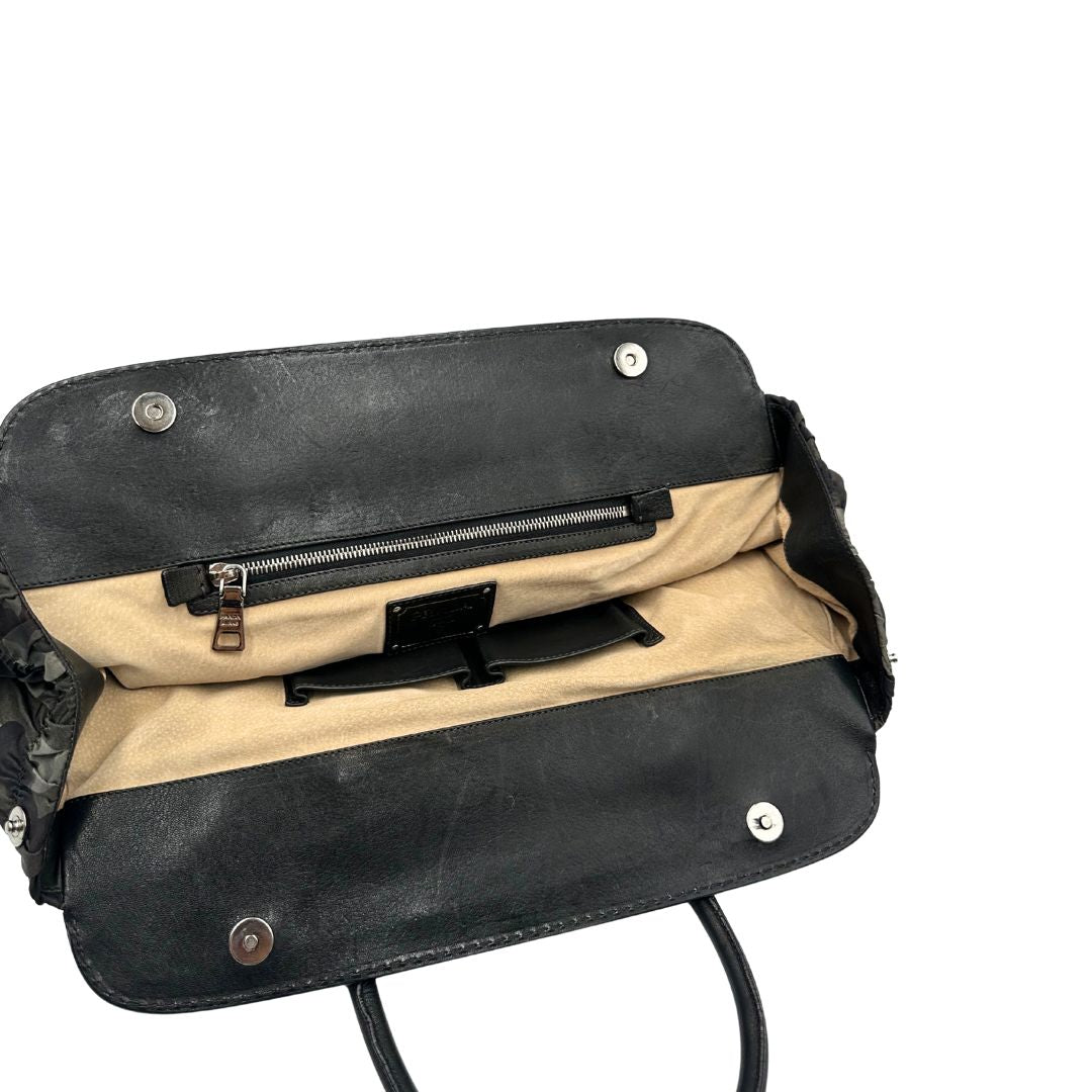 Interno di una Borsa Prada in tessuto nylon goffrato trama camouflage nelle tonlità del verde, finiture in pelle nere e inserti metallici argentati; dotata di doppi manici stondati. Completa di dustbag. Originale, usata, di lusso, in ottime condizioni.