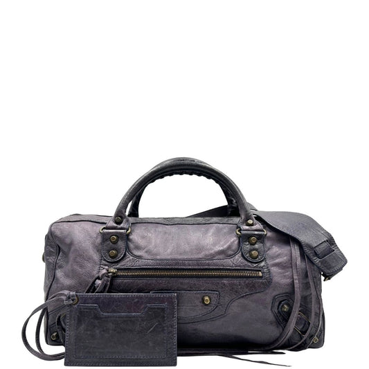 Front di unaBorsa Balenciaga in pelle viola scuro effetto invecchiato con parti metalliche ottone anticato, munita di doppi manici con dettaglio intreccio, e una tracolla amovibile e regolabile con spallaccio. Completa di dustbag. Originale, usata, di lusso, in ottime condizioni.