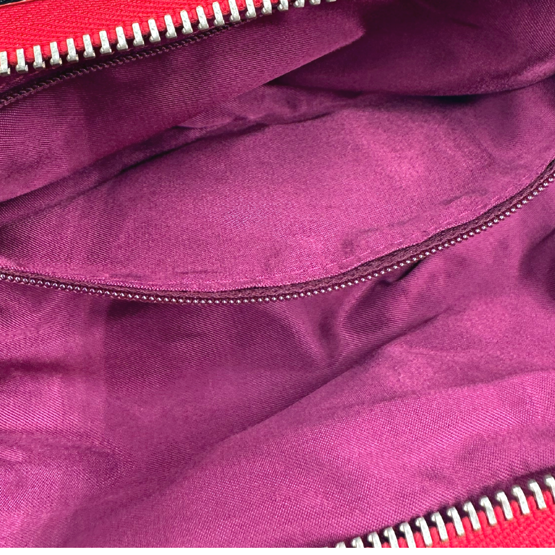 Pochette Paciotti in pelle color rosso aranciato con parti metalliche dorate; impreziosita con un maxi fiocco con strass e nappina con anelli. Completa di dustbag.