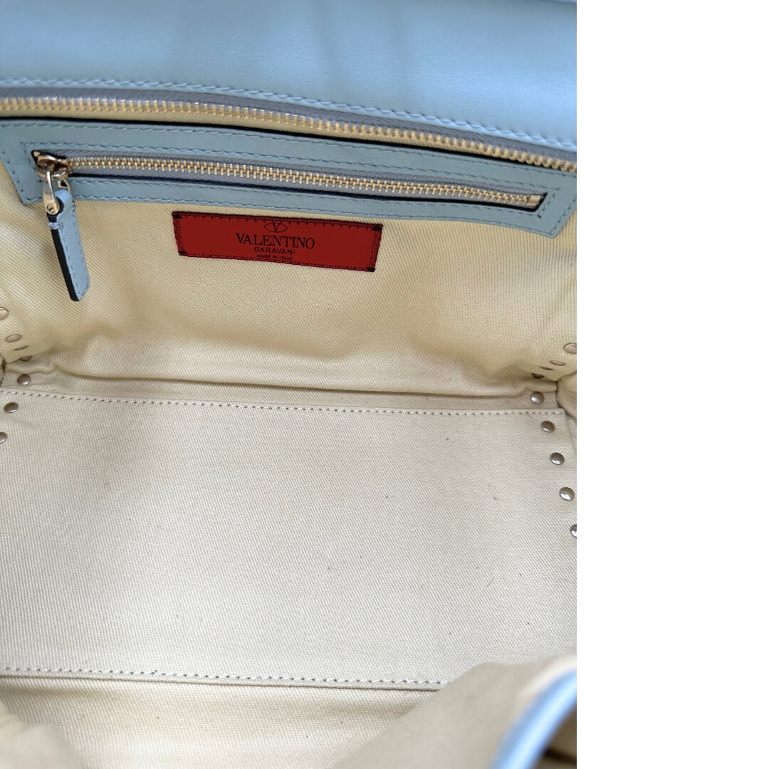 Borsa Valentino Garavani in pelle color azzurro baby e parti metalliche oro chiaro; munita di doppi manici e una tracolla amovibile impreziosita da borchie piramidali. Completa di dustbag e borchie sostitutive.