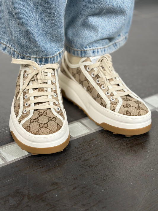 Ragazza che indossa delle scarpe Gucci realizzate in tela monogram GG con profili in tela bianca e para color crema, usate, originali, second hand, in condizioni eccellenti.