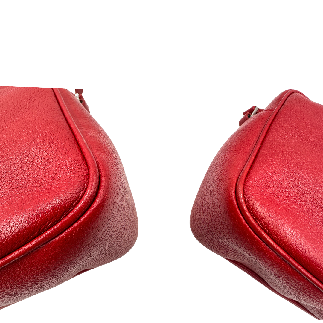 Angoli, Borsa Saint Laurent in pelle rossa con hardware argentato decorativo, iconiche iniziali YSL al centro e nappa decorativa. Indossabile a tracolla. Originale, usata, di lusso, in ottime condizioni.