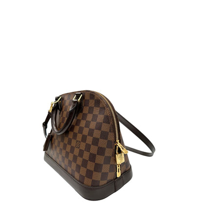 Lato sinistro, Strutturata borsa Alma PM LV in canvas Damier Ébène e hardware dorato, indossabile a mano oppure a tracolla.