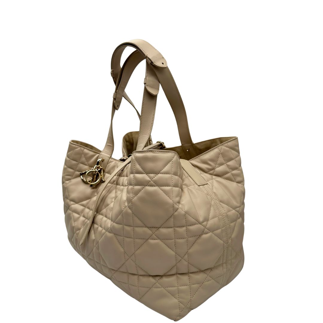 Lato sinistro, Borsa Christian Dior in pelle beige con impunture Macrocannage e parti metalliche dorate; munita di doppi manici regolabili e una pochette estraibile; da portare a mano o a spalla. Completa di dustbag, di lusso, originale, ottime condizioni. 