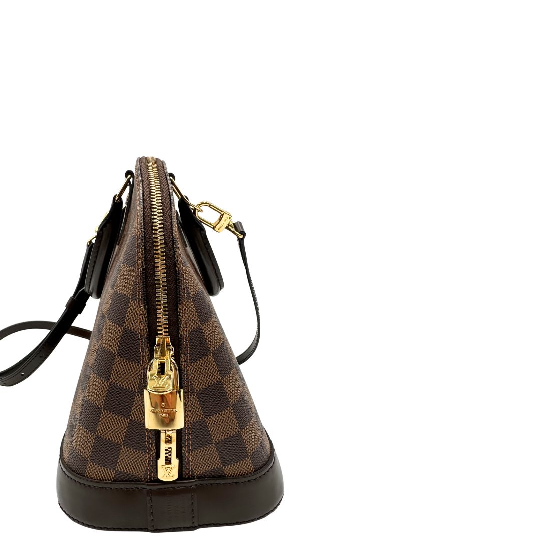  Strutturata borsa Alma PM LV in canvas Damier Ébène e hardware dorato, indossabile a mano oppure a tracolla.