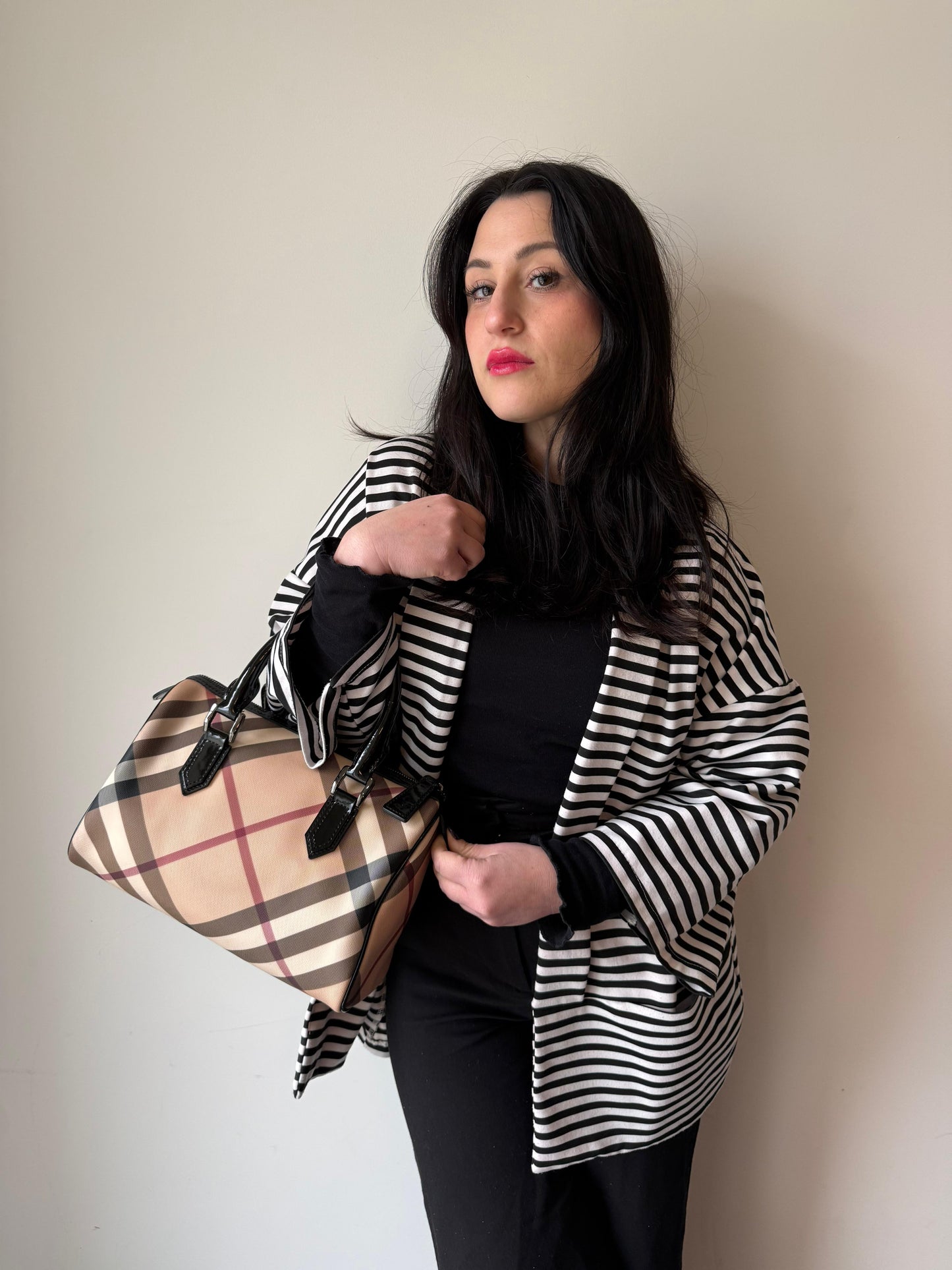 Ragazza che indossa una borsa a mano Burberry in canvas tartan e finiture nere lucide, usata, originale, second hand, in ottime condizioni.