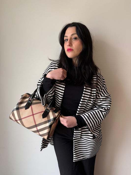 Ragazza che indossa una borsa a mano Burberry in canvas tartan e finiture nere lucide, usata, originale, second hand, in ottime condizioni.