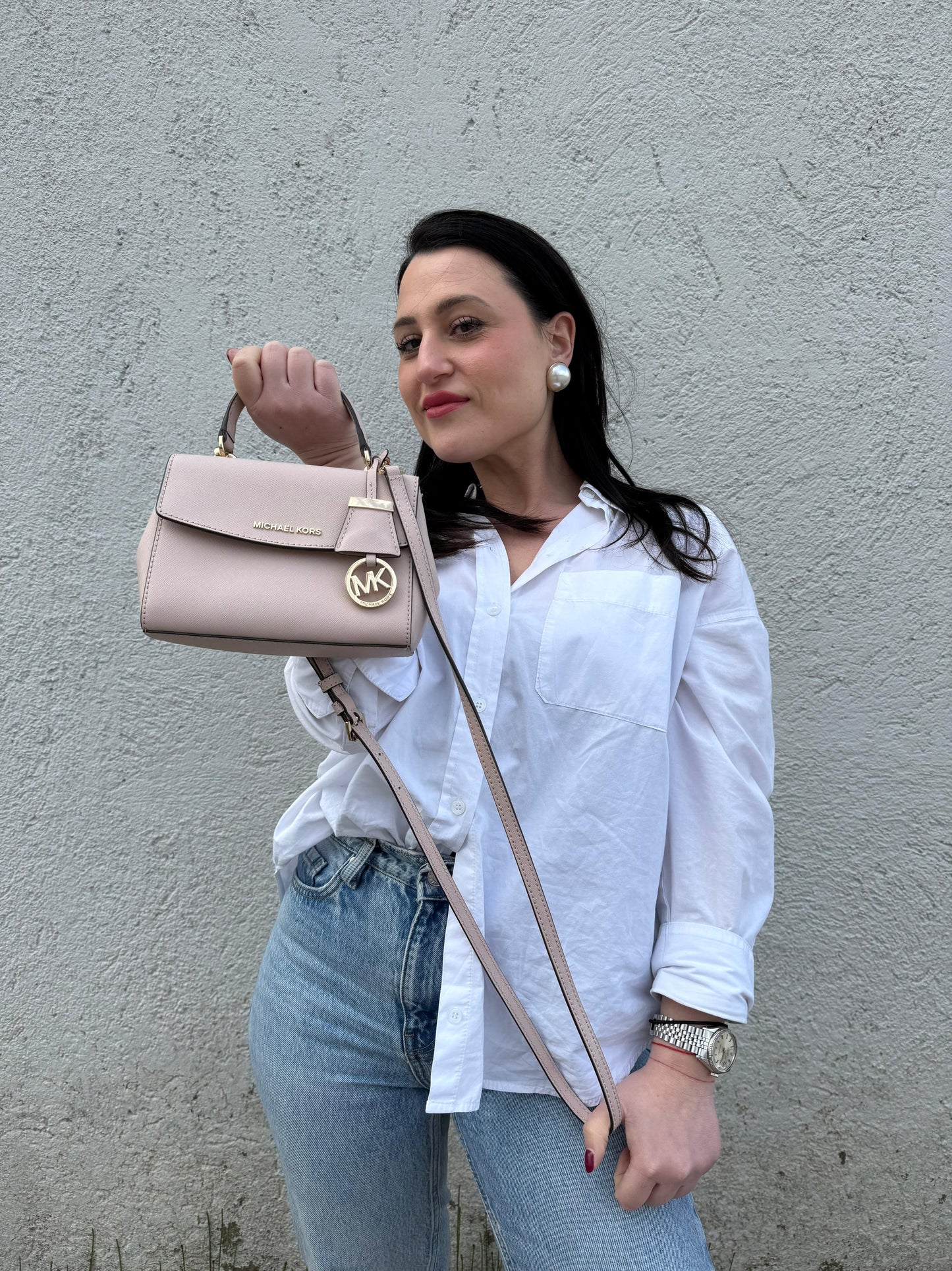 Ragazza che indossa una borsa MK strutturata in color rosa cipria e parti metalliche dorate, usata, originale, second hand, in condizioni eccellenti.