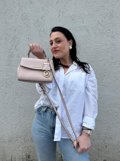 Ragazza che indossa una borsa MK strutturata in color rosa cipria e parti metalliche dorate, usata, originale, second hand, in condizioni eccellenti.