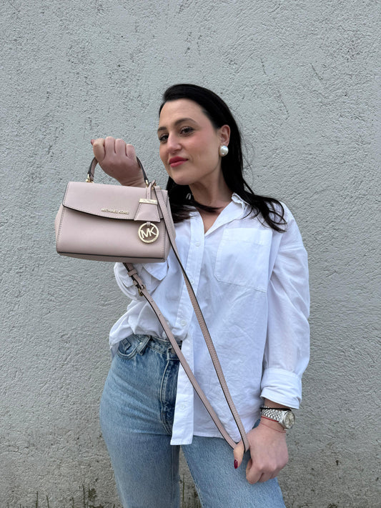 Ragazza che indossa una borsa MK strutturata in color rosa cipria e parti metalliche dorate, usata, originale, second hand, in condizioni eccellenti.