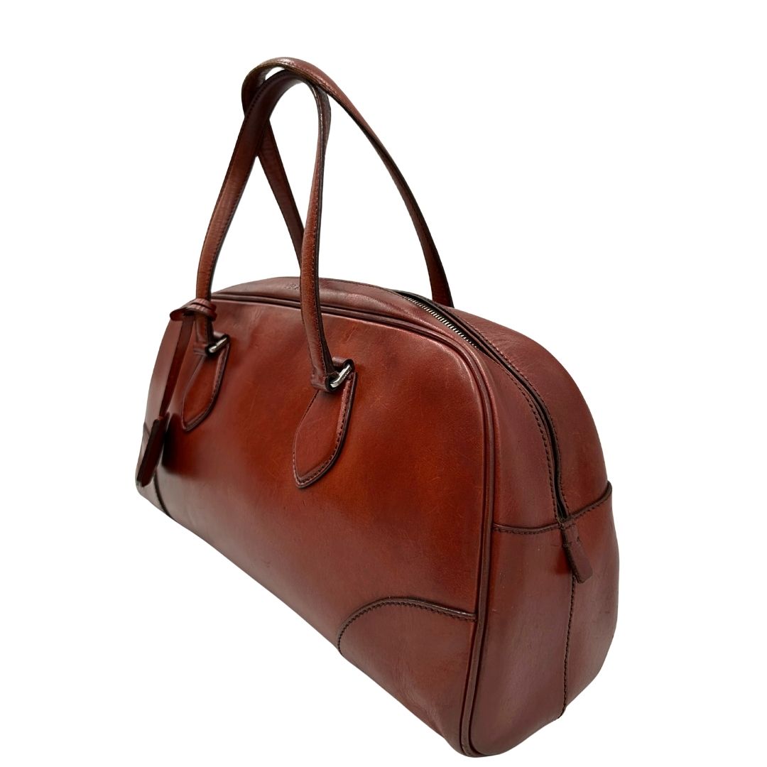 Borsa Prada in pelle color terracotta con parti metalliche argentate; munita di doppi manici. Completa di dustbag, lucchetto e chiavi, di lusso, originale, ottime condizioni.