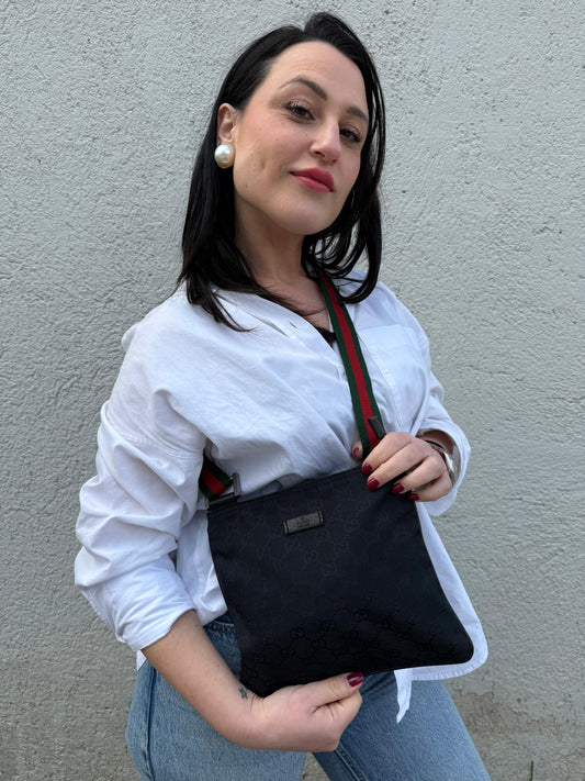 Ragazza che indossa una borsa Gucci GG con tracolla Web regolabile e finiture in pelle nere, usata, originale, second hand, in ottime condizioni.
