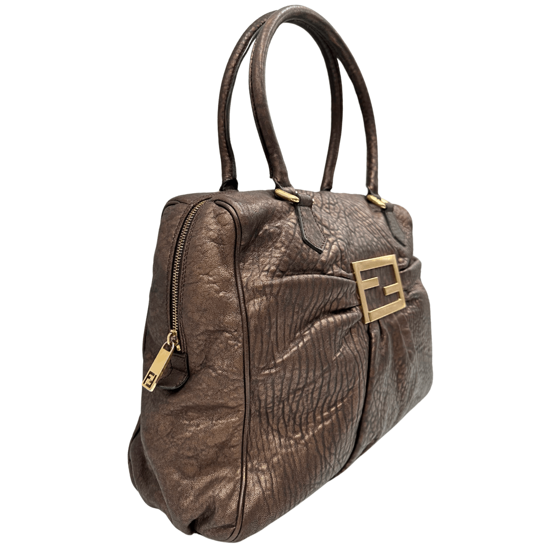 Scopri la shopper Fendi in pelle bronzo con l'iconico logo in metallo dorato. Eleganza e stile in un design spazioso e versatile.