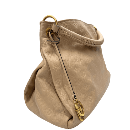 Louis Vuitton Artsy MM in pelle Monogram Empreinte beige. Elegante e spaziosa, con dettagli intrecciati e charm dorato. Perfetta per un look sofisticato.