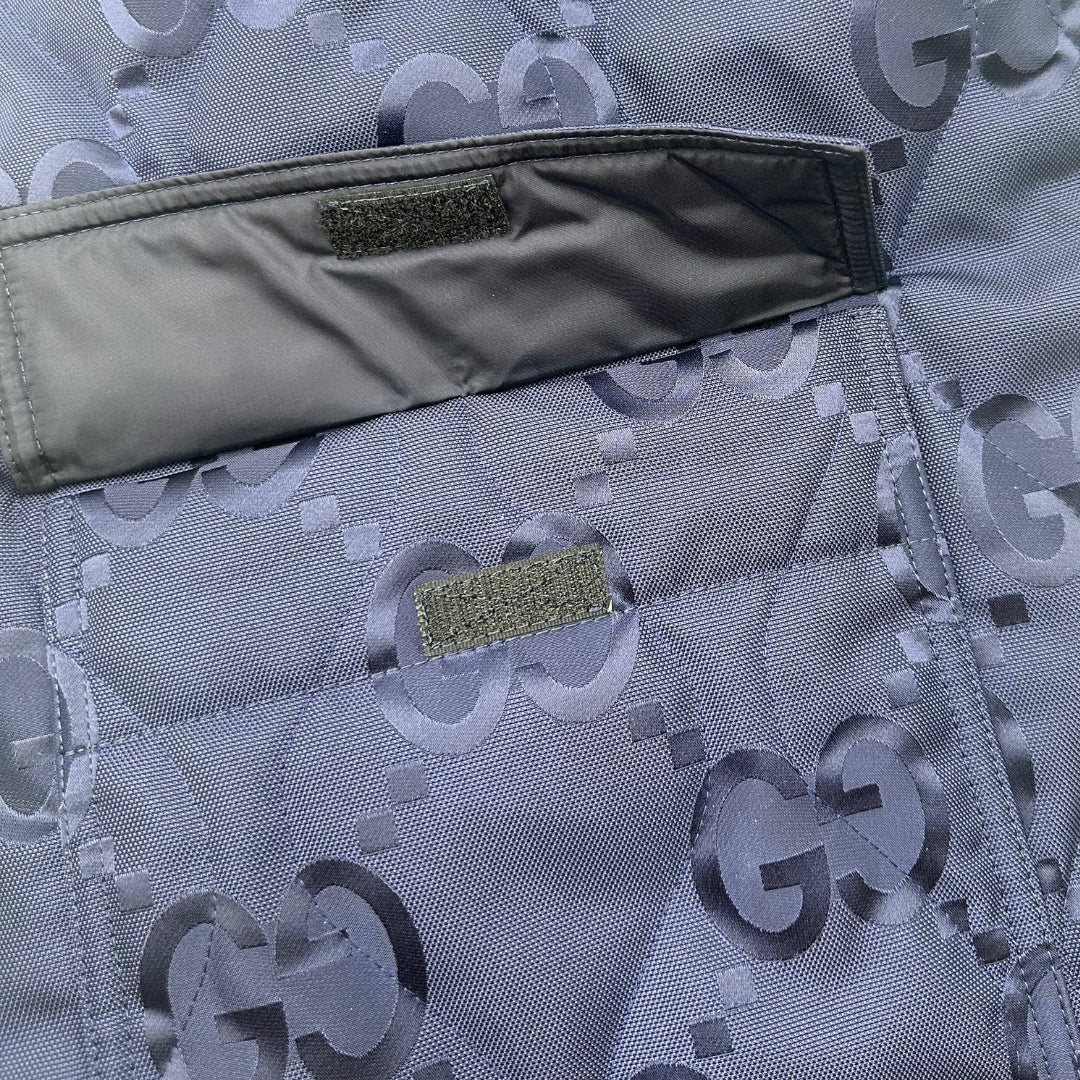 Tasca del retro dello Smanicato Gucci in 100% Poliammide blu navy con iconica trama GG Jumbo. Chiusura con cerniera, doppie tasche laterali e una sul retro con chiusura a strappo. Rifinito con parti metalliche argentate. Originale, usato, condizioni eccellenti. 